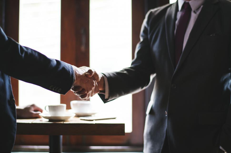 Two men in business suits shake hands.