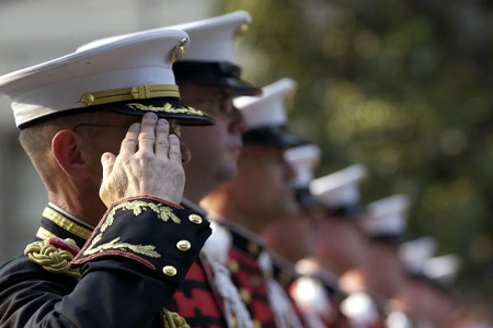 US Marines stand in line with one saluting.