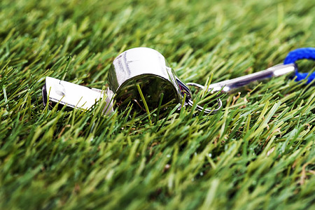 Coaches whistle with blue cord lays on grass.