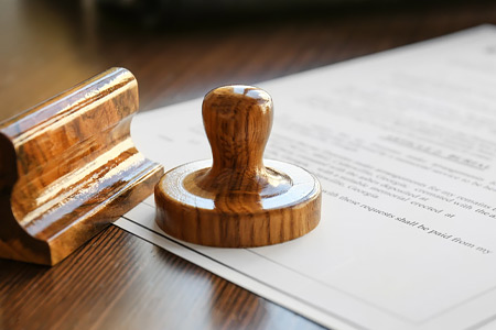 Stamper sits on top of a legal document on a wooden desk.